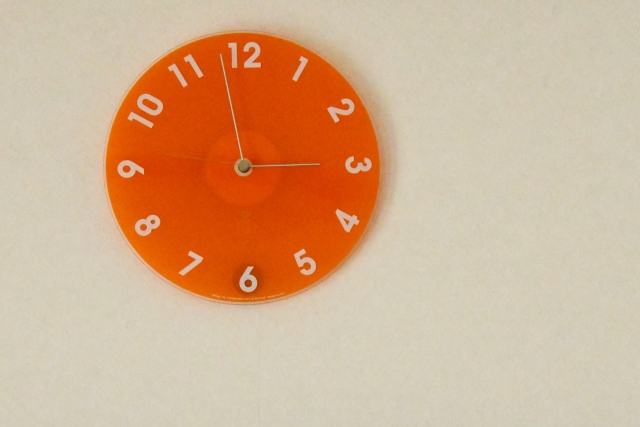 もうすぐ3時になるオレンジの壁掛け時計