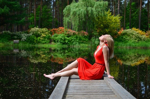 神秘的な湖の近くに座る赤いドレスを着た女性