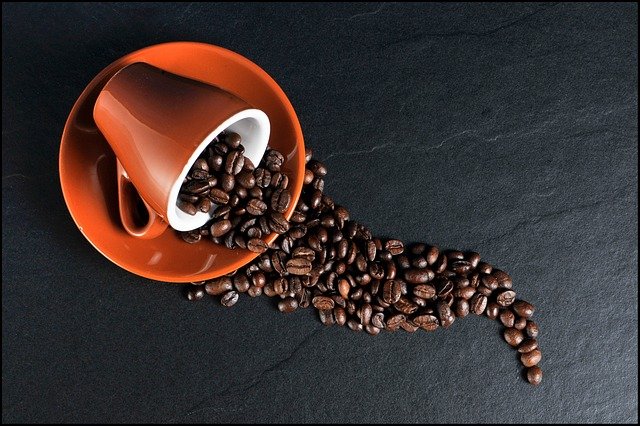 赤いカップから零れ落ちるコーヒー豆