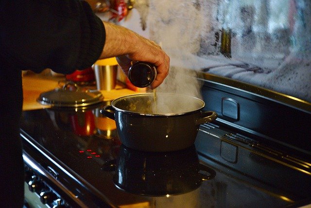 鍋を使って料理をする男性