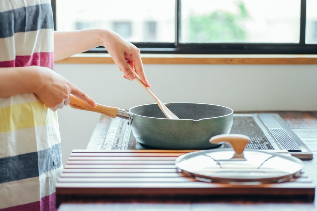 IHコンロに鍋をかけて調理する女性