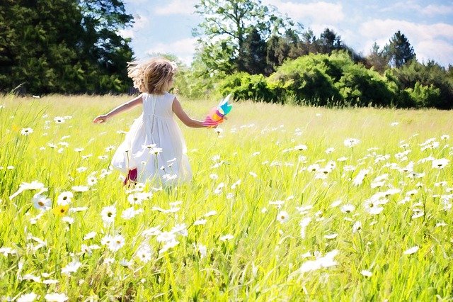 花畑で風車を持って走る小さな女の子