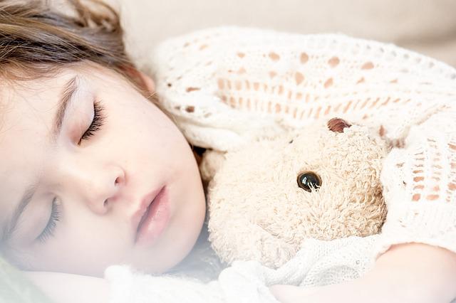 熊の人形を抱えて寝る女の子